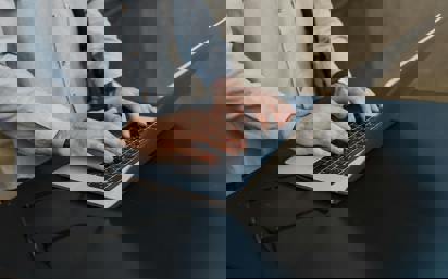 Student's hands typing on laptop participating in JD-Next Law School Admission Assessment