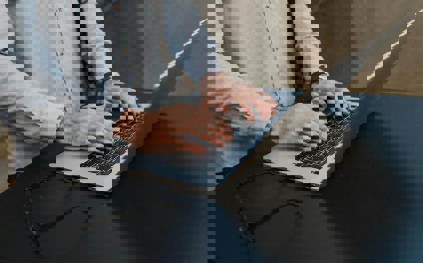 Student's hands typing on laptop participating in JD-Next Law School Admission Assessment