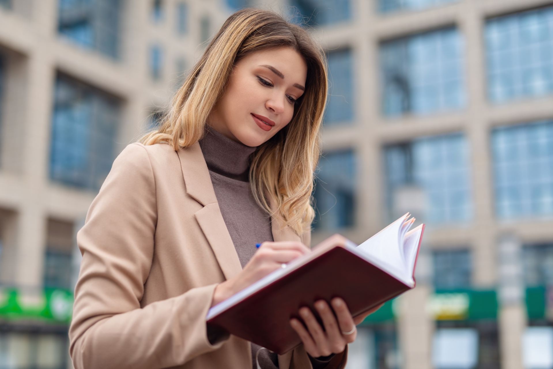 Woman standing outside writing notes about JD-Next Admissions Assessment in her notebook