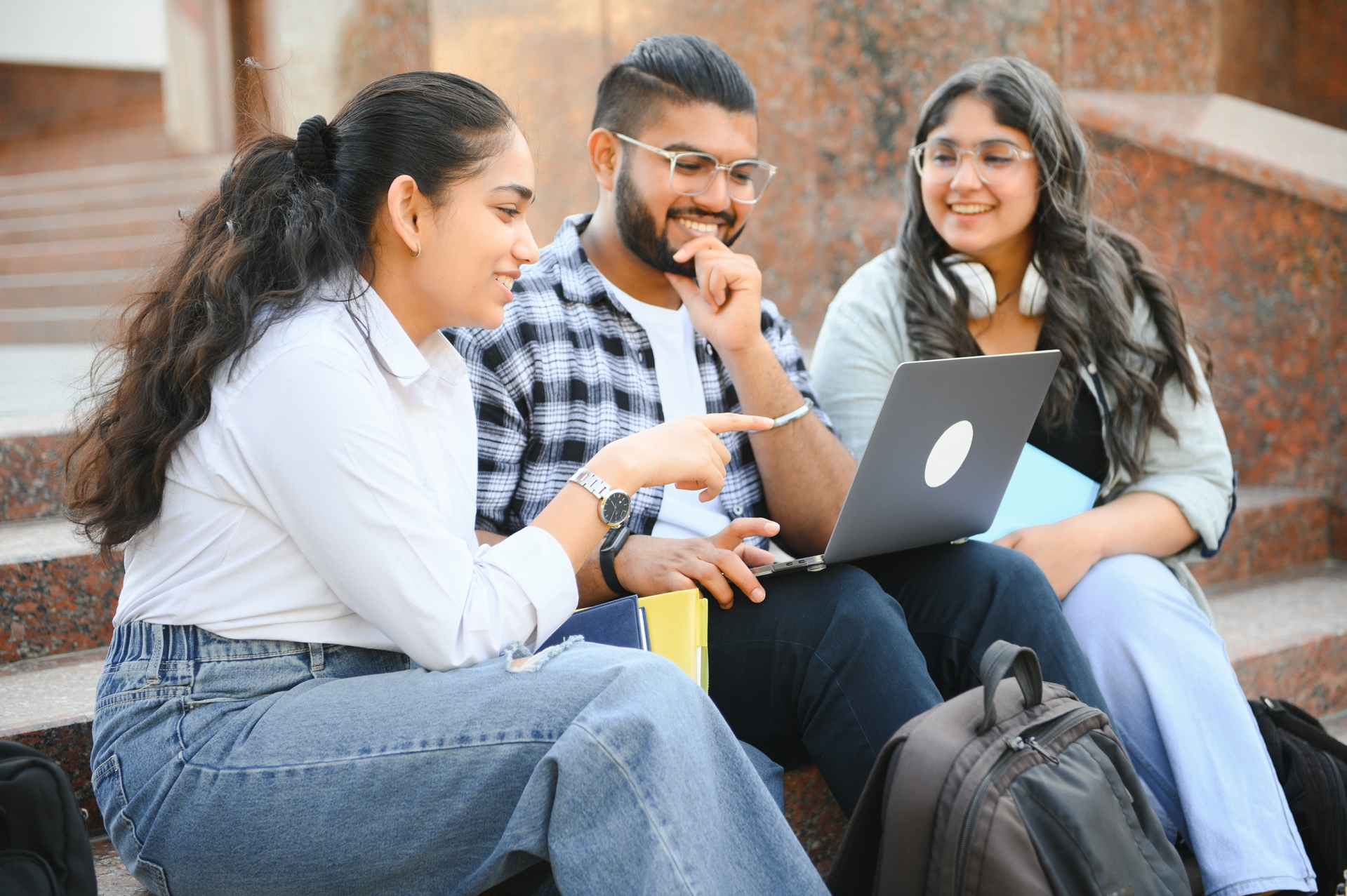 Pre-Law Students Sitting on Steps Looking at Laptop Discussing Taking JD-Next Admissions Assessment