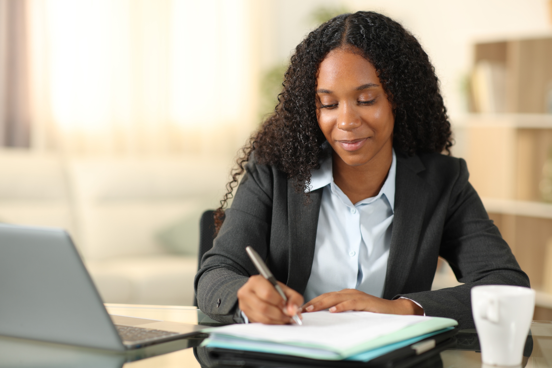 female law student on laptop, taking notes on JD-Next Admission Assessment